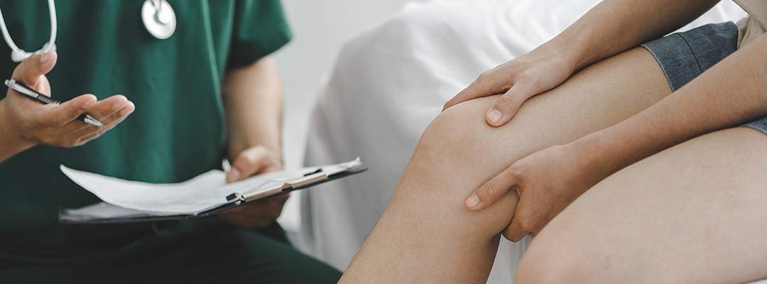 Doctor consulting with patient about knee treatment in clinic