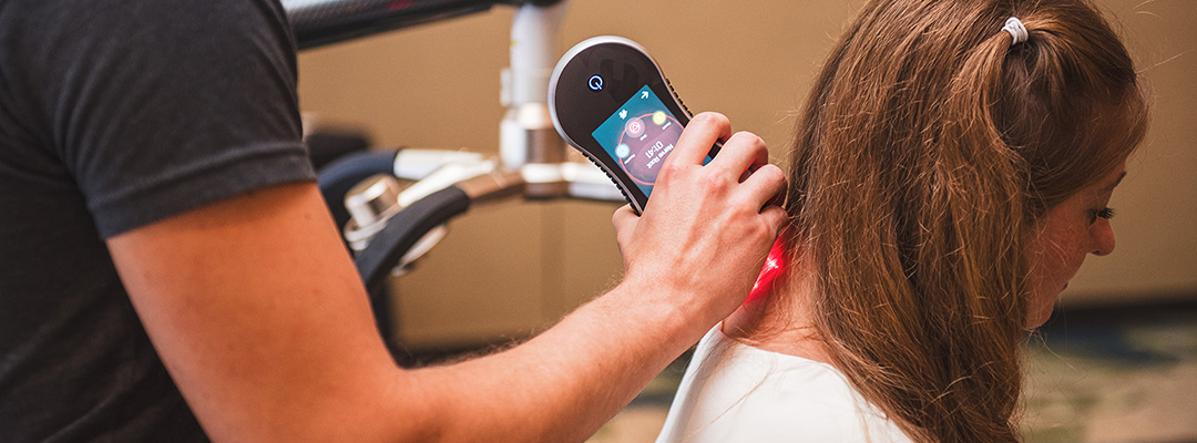 Handheld Erchonia laser being used for therapy on athletes neck.