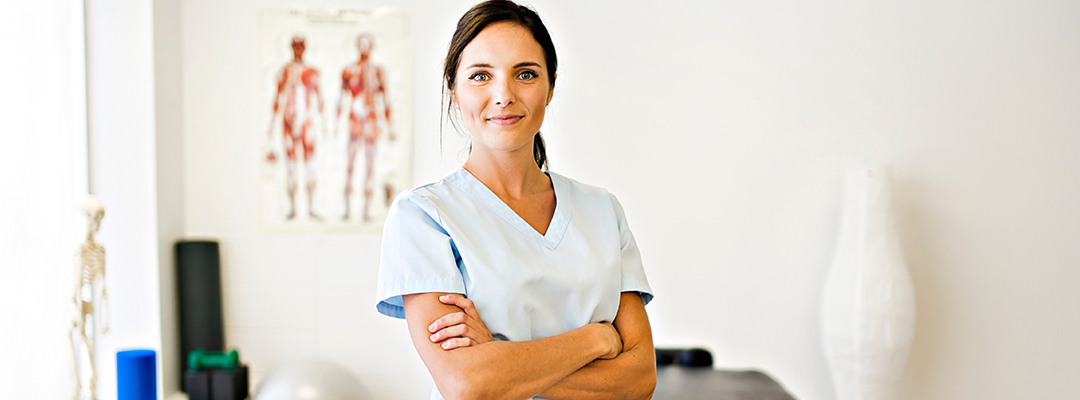 A Portrait of a physical therapist woman smiling in uniform in her office.