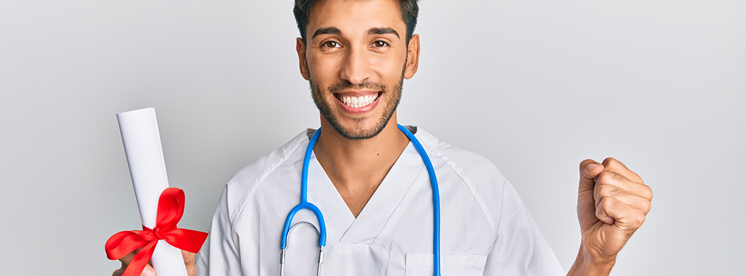 Happy male doctor celebrating graduation, holding diploma with a stethoscope around his neck