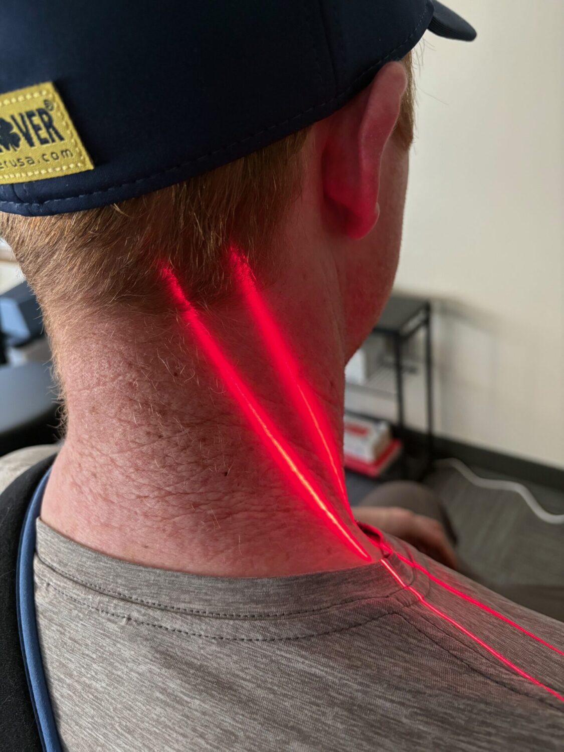 A red XLR8 laser line on a patient’s neck