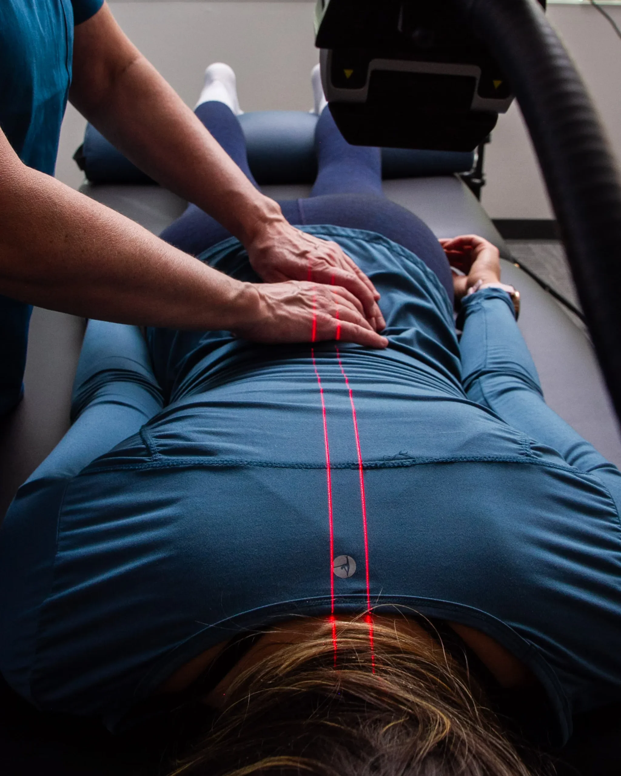 A red XLR8 laser line on a patient’s low back