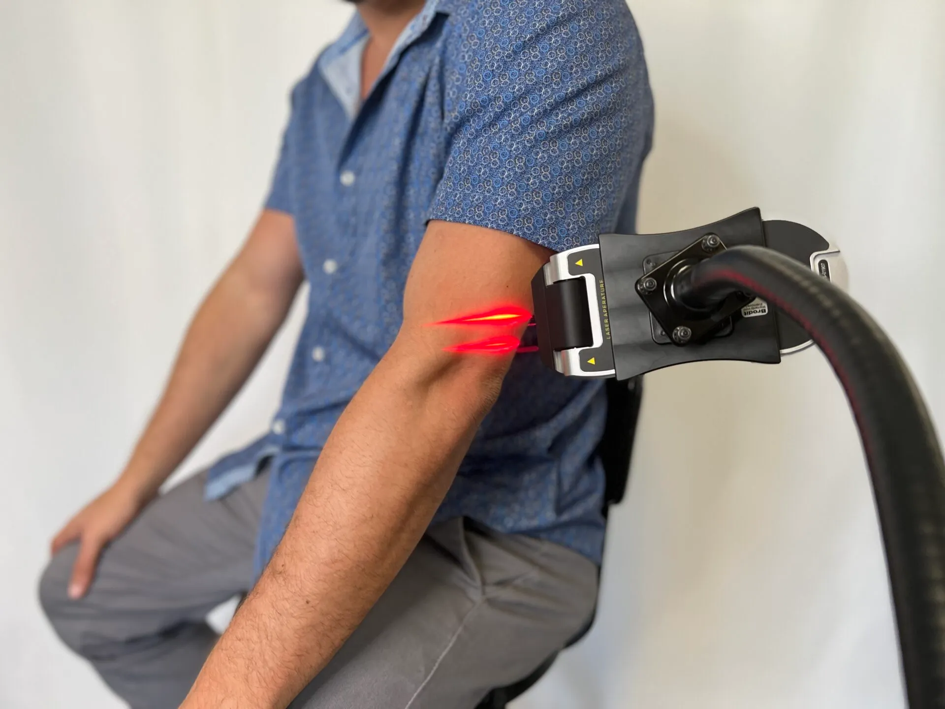 An Erchonia handheld laser on a stand treating a patient’s shoulder
