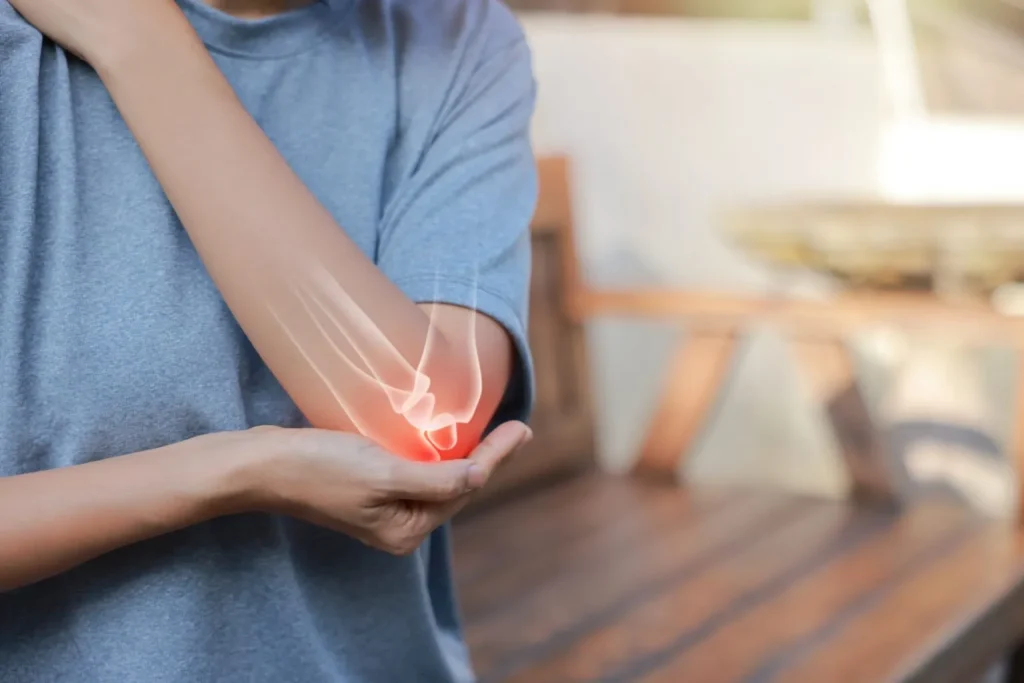 Person gripping a sore elbow with the joint highlighted in red, illustrating tennis elbow tendonitis