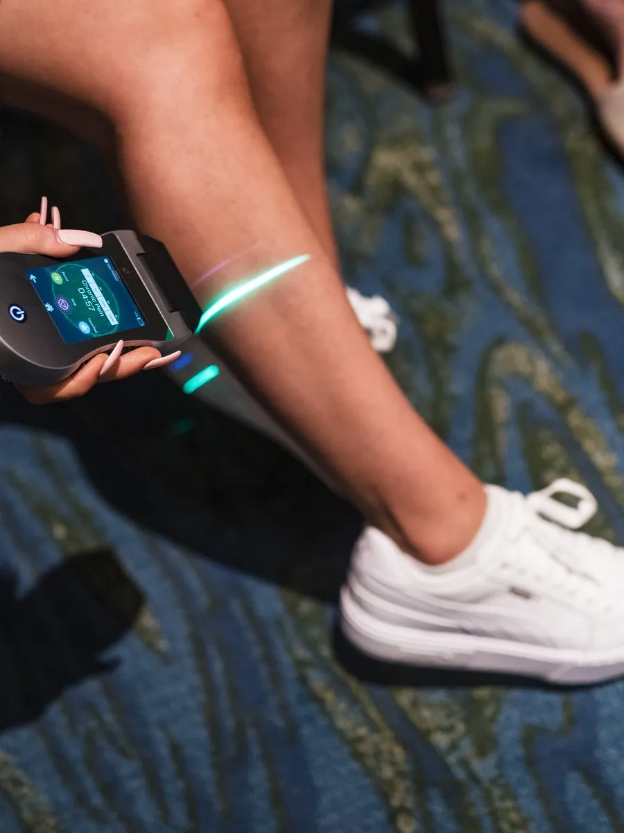 A practitioner applying a handheld laser to a patient’s ankle