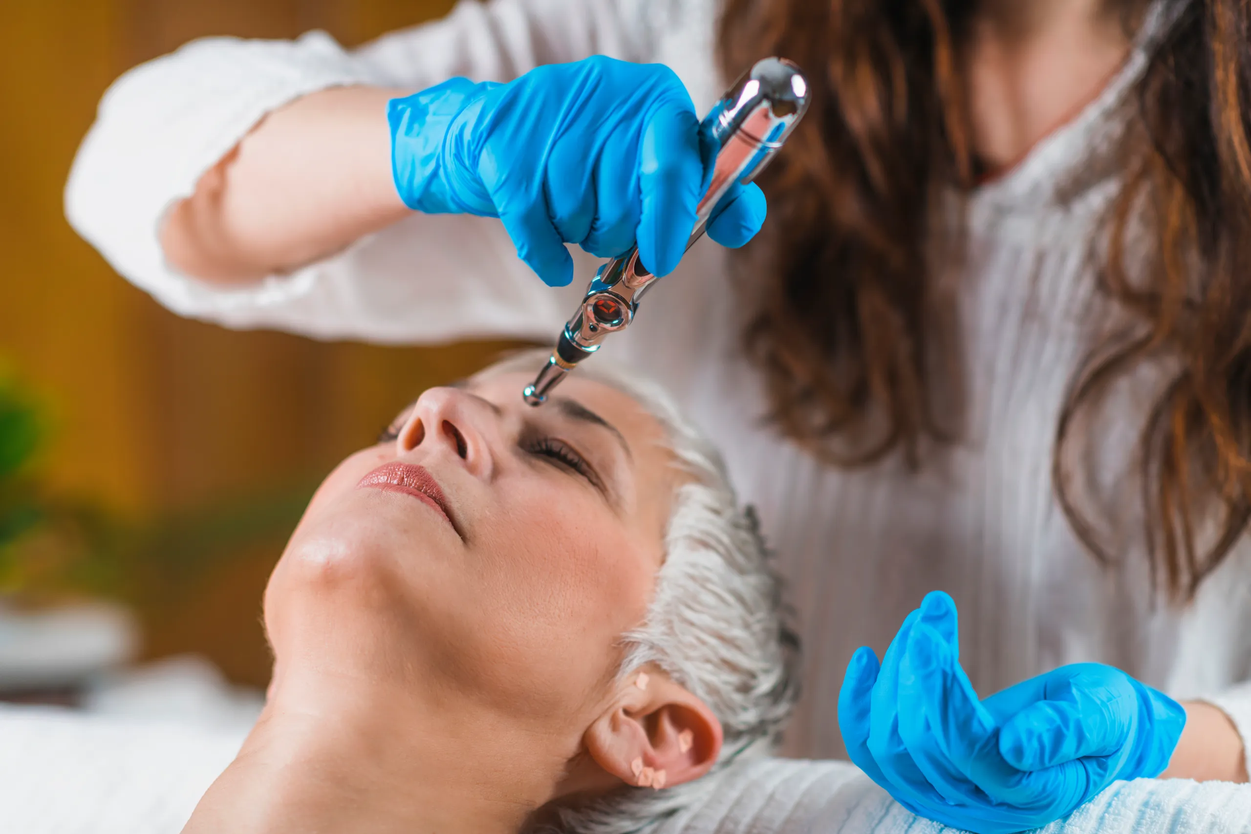 elderly woman receiving head treatment with electronic laser therapy